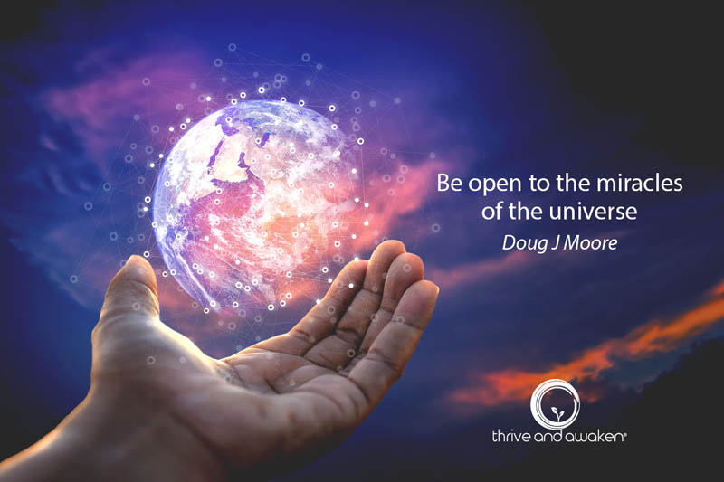 A person's hand is holding the earth w a quote from Doug: Be open to the miracles of the universe